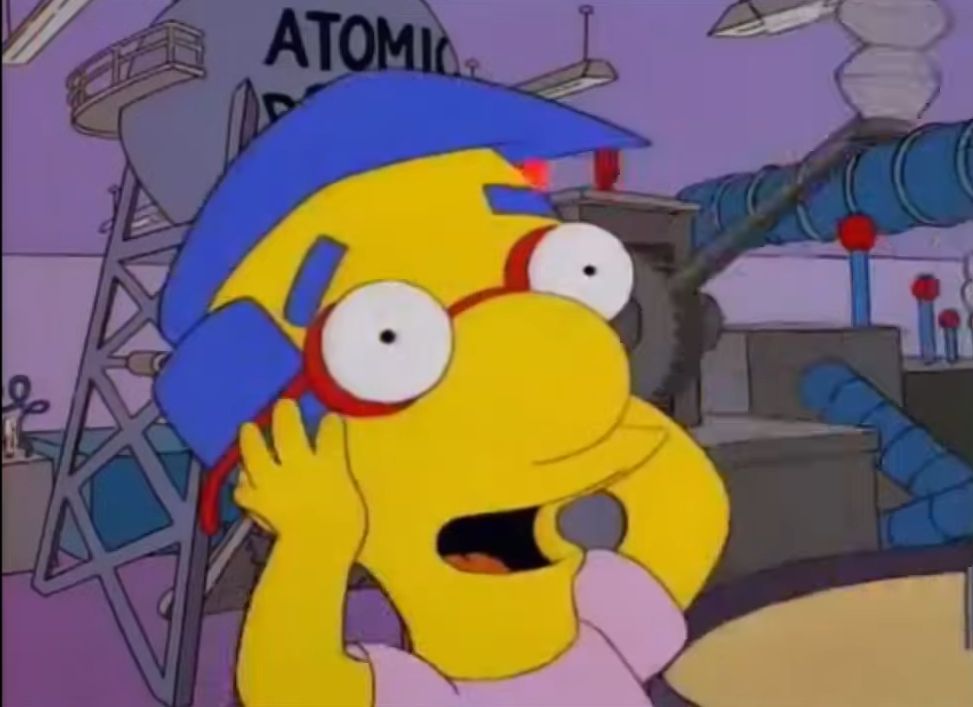 still from the simpsons: milhouse holds his head as he looks around the cracker factory in shock and glee