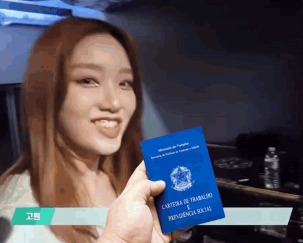 a woman holding a blue card that says carteira de trabalho e previdenca social