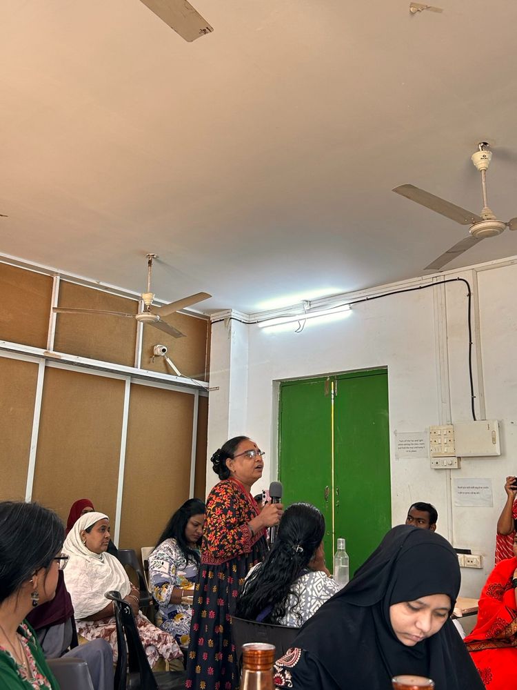 
A woman speaking in the mic at CREA X TISS's sanitation training. She is surrounded by other participants attending the session.