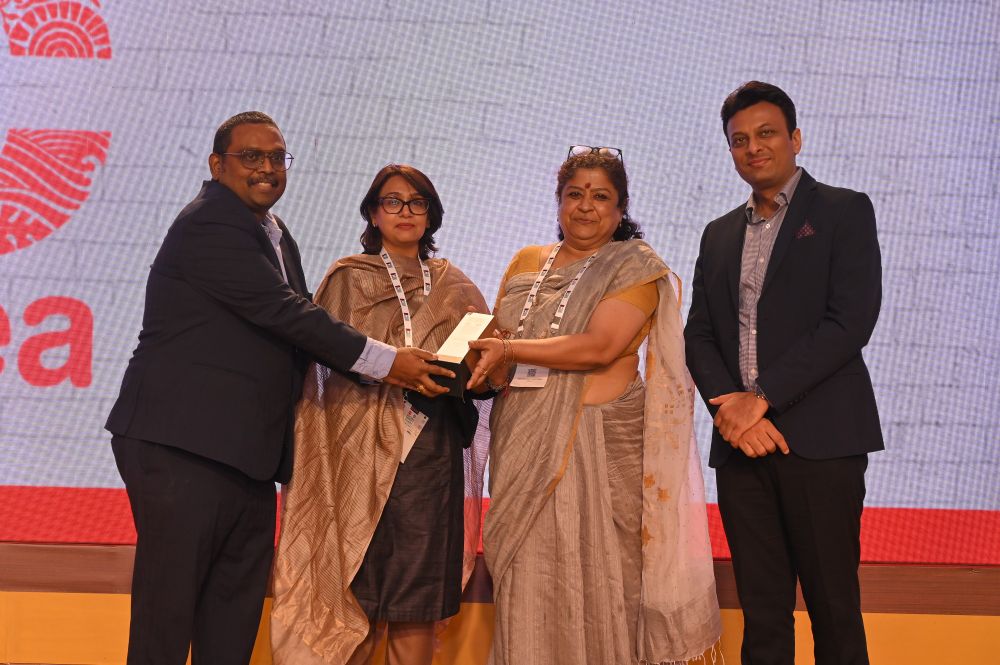 Anuradha Chatterjee and Aditti Gogiyaa receiving the Times of India’s Leadership in Advancing Gender Equality award for CREA from two presenters on stage.