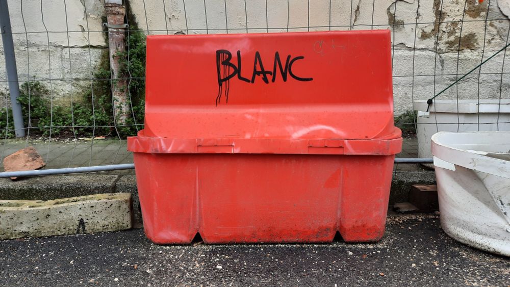 Le mot blanc écrit en lettres noires sur un plot de chantier en plastique rouge