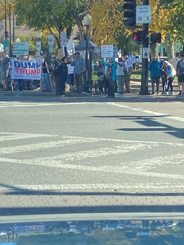 Group of people on a downtown street corner in Prescott Arizona today. Many anti trump signs.