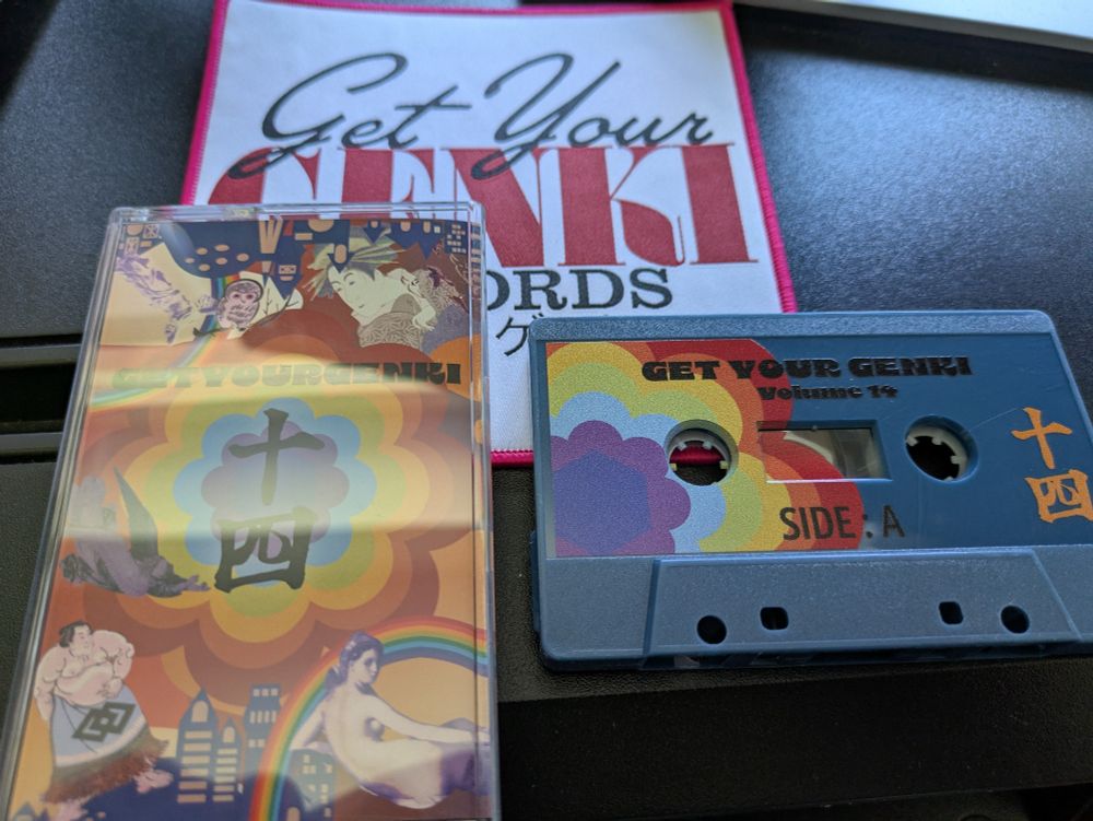 A cassette tape, blue with a 60s style rainbow coloured flower print, 