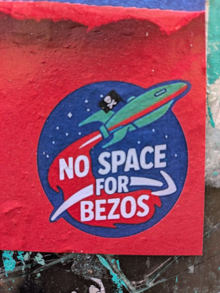 Detail of a protest poster in Venice showing a logo before red background: a light blue space rocket (based on Futurama) flying a pirate flag on a blue circle of space, red exhaust flames, white slogan, 