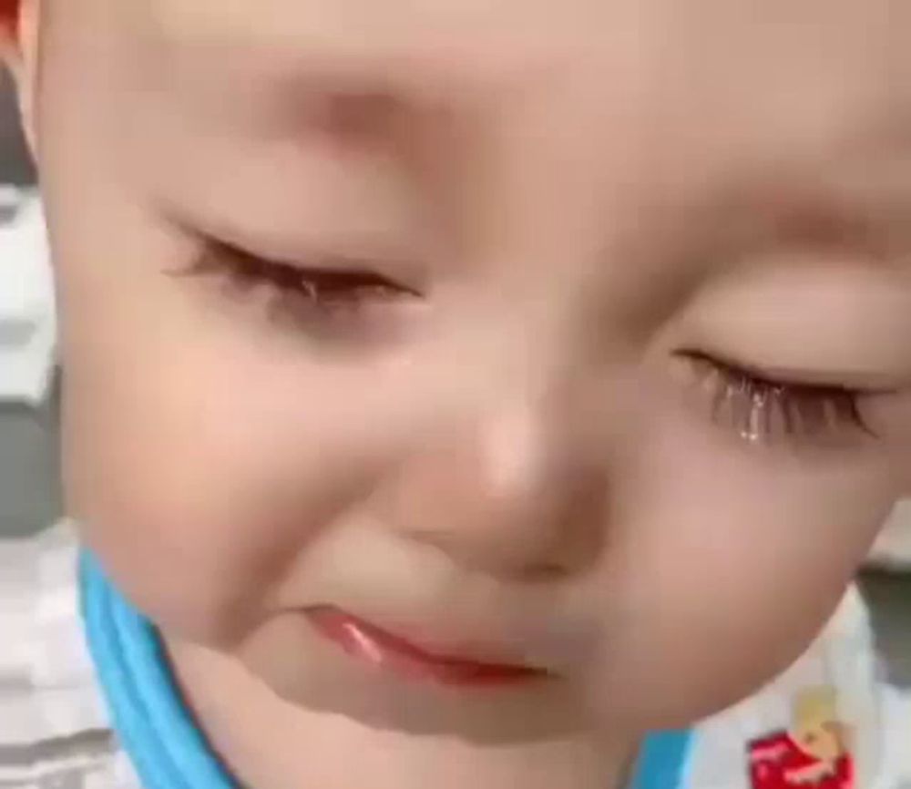 a close up of a baby 's face with a tear running down his eye .