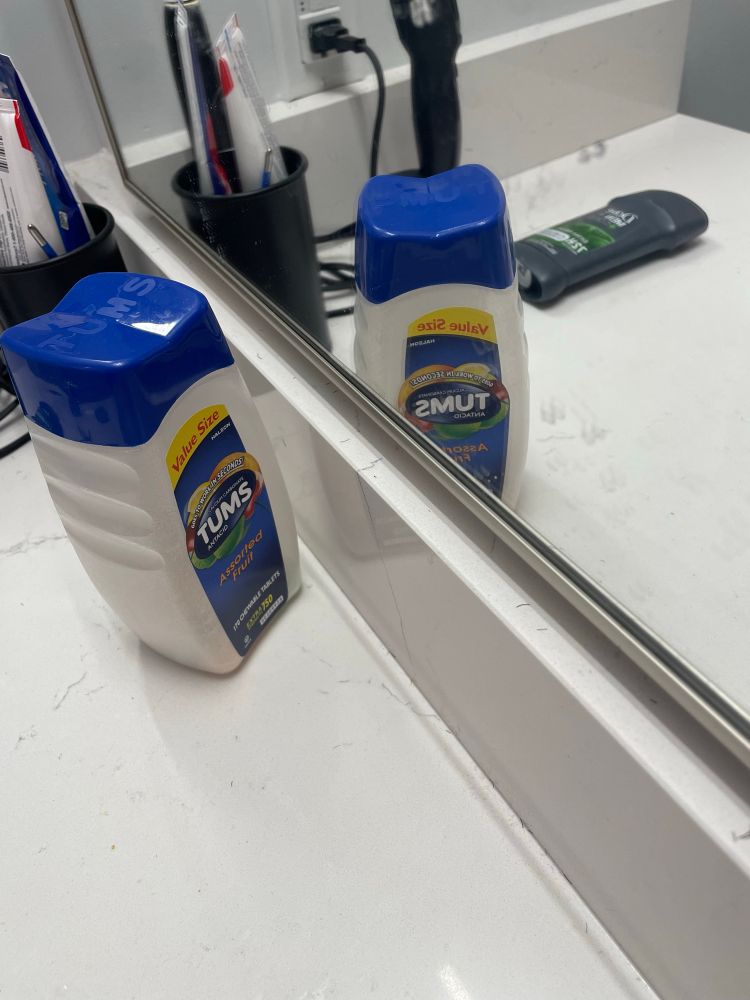 A bottle of Tums (antacid) positioned next to a mirror in such a way that the reflection reads “smut”