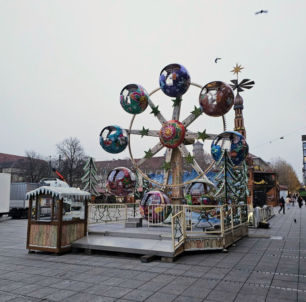 Ein kleines Riesenrad mit 8 Kabinen für kinder steht auf dem schlossplatz in Stuttgart. Es ist nebelig und diesig im Herbst. Im Hintergrund der Aufbau für den Stuttgarter Weihnachtsmarkt 