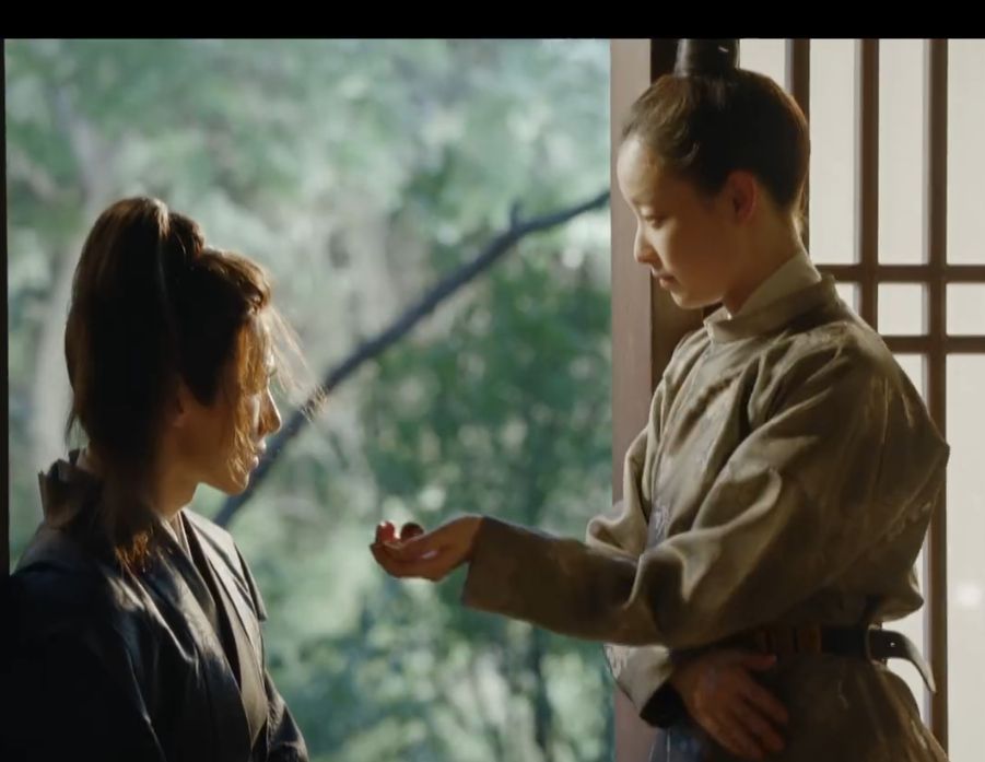 Feng Zhi Wei standing by an open window and offering her bodyguard a walnut, but the body language is very confident and slightly seductive and definitely masculine - The Rise of Phoenixes, episode 23