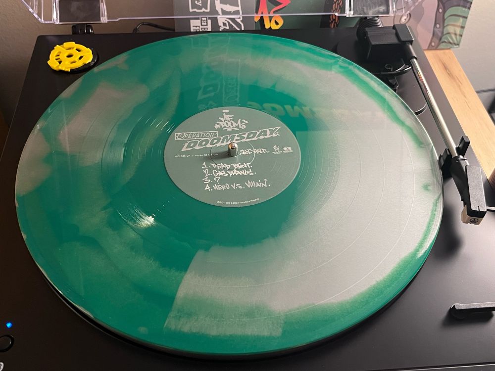 disc two of MF doom's album "Operation: Doomsday" (normally stylized in all caps but changed here for e-reader legibility) sitting on a turntable.The vinyl is mostly green with silver swirls