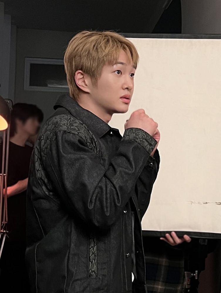 Onew with both hands held in fists in front of him and a frightened expression on his face 