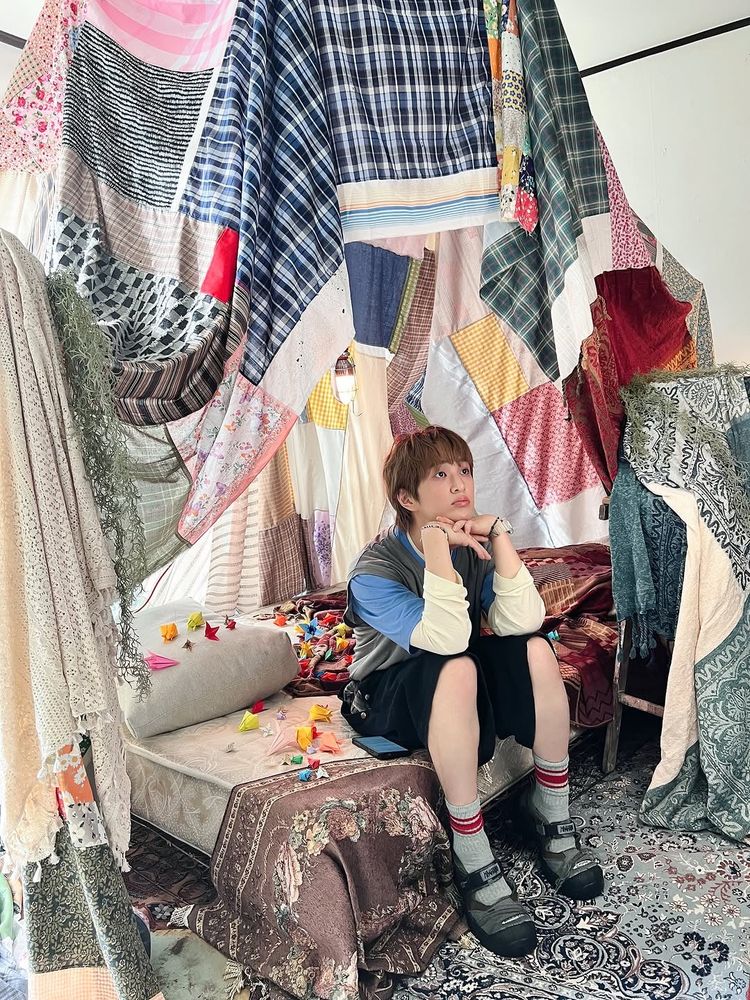 Onew sitting with his head resting on his hands, looking thoughtful 