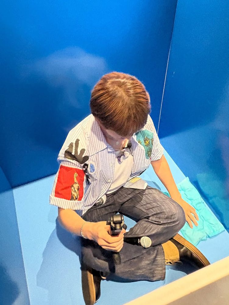 Onew sitting inside the folded box and looking down 