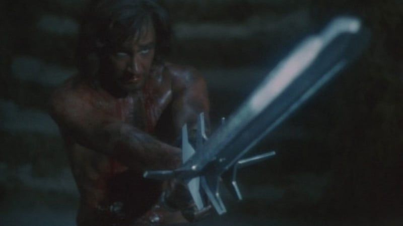 A bloody barbarian-looking dude in a cellar with a three-bladed sword.