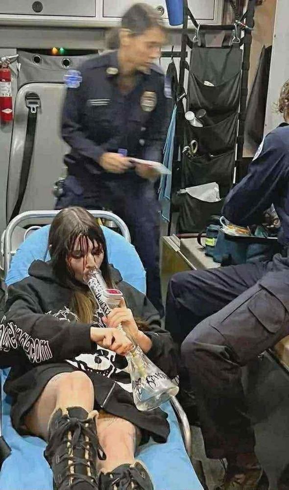 Girl smoking out of bong laying in a stretcher in an ambulance