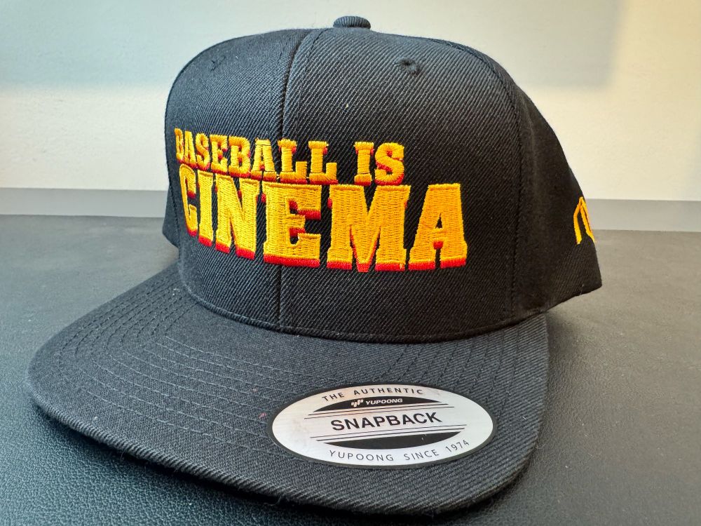 A SnapBack baseball cap. On its front, the text: BASEBALL IS CINEMA