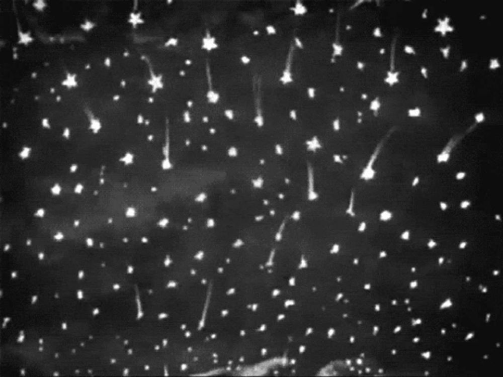 a black and white photo of a night sky with stars falling