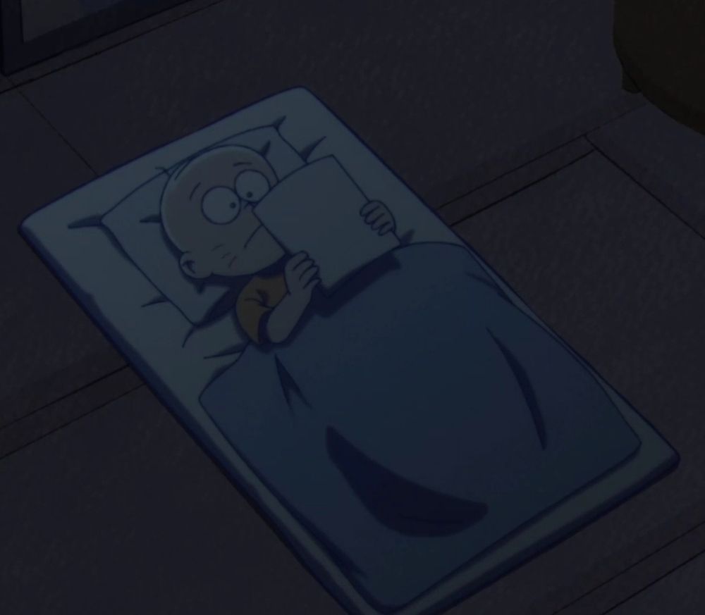 A dark screenshot of Chibita laying on his back in his futon, infront of him he holds up a piece of paper.