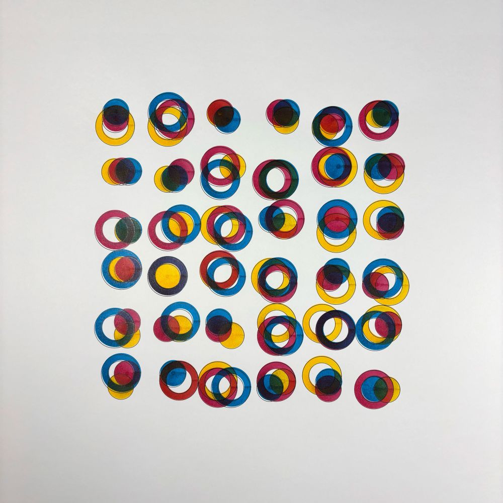 A grid-like arrangement of overlapping circles composed of cyan, magenta, and yellow segments. Each circle varies in shape, alignment, and layering, producing a wide array of blended colors.