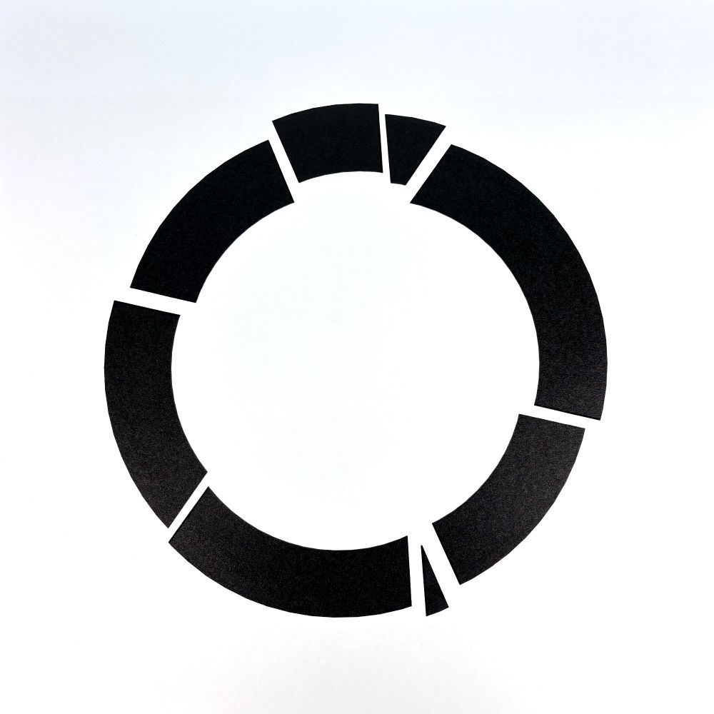 A minimalist abstract image of a black circular ring, segmented into seven distinct pieces with varying gaps. The form is centered on a white background.