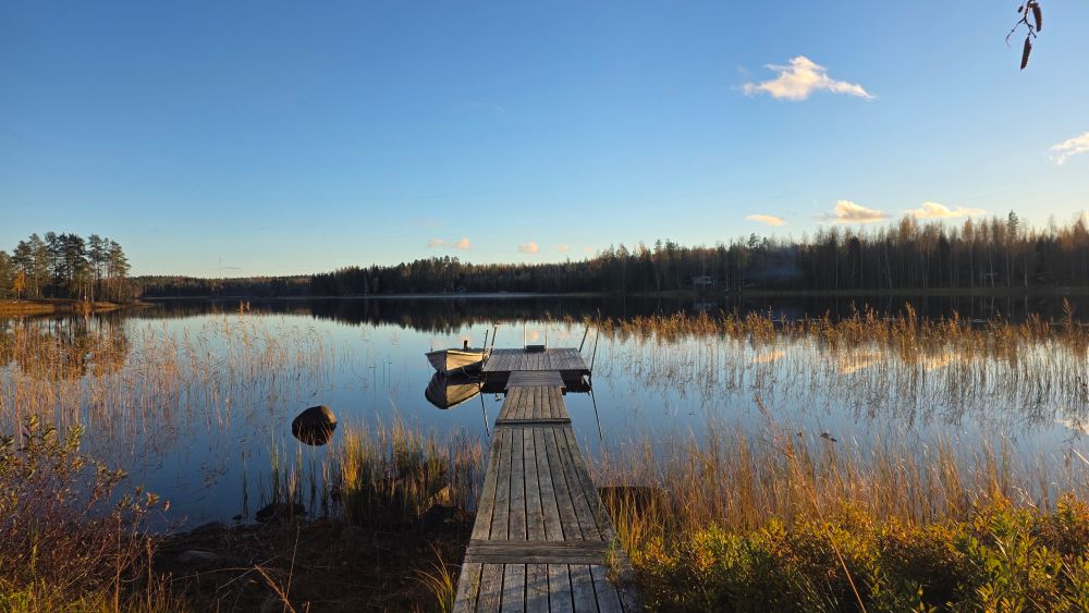 Picture of a lake with a boat and a pier. 