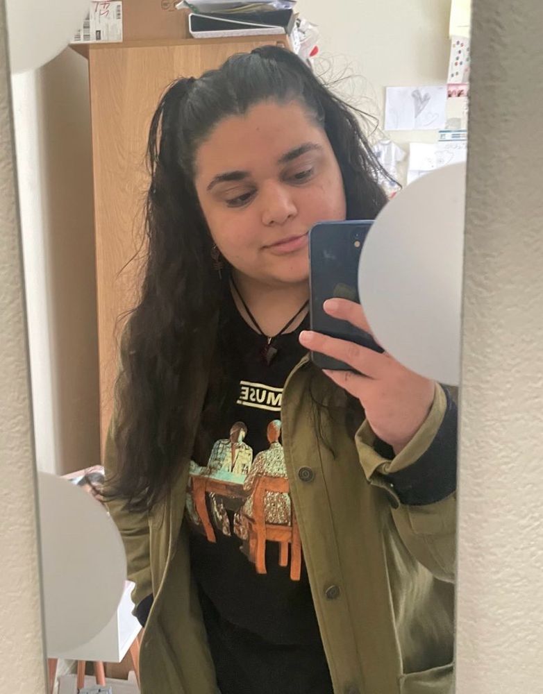 mirror selfie of me wearing a muse sweatshirt, khaki green jacket and hand in pocket