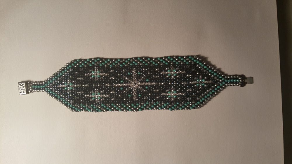 A beaded bracelet with a dark blue background, with seven light blue and silver stars and edging.