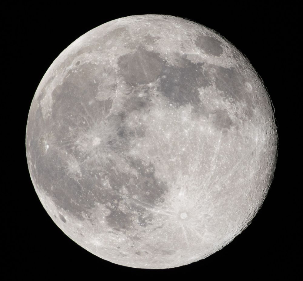 A crisp photo of the full moon, with just a fringe of shadow on the right edge showing crater rims in relief.