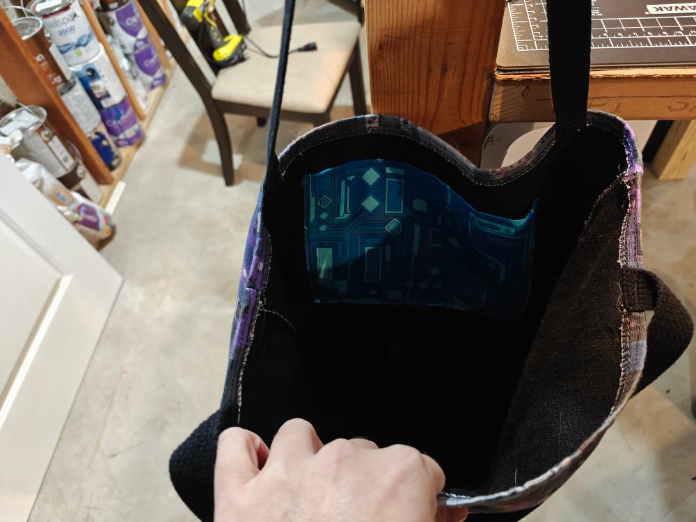 Me showing the inside of the same tote bag while it's hanging. The floor of the basement and the table from the previous images can be seen.