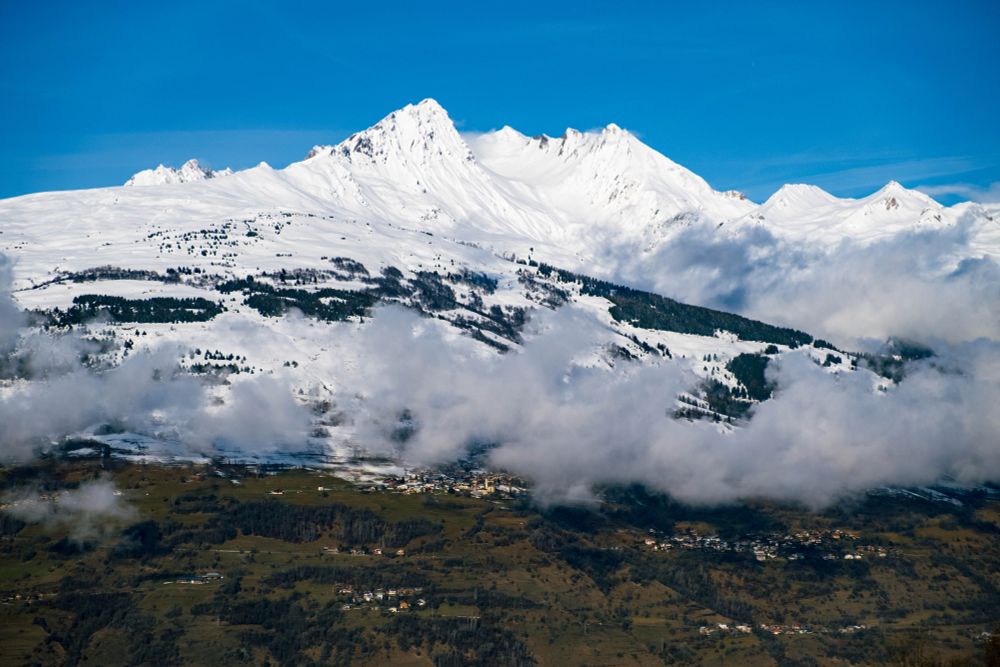Une montagne, enneigée au sommet, mais pas à sa base, les deux sont séparés par une ligne de nuages.