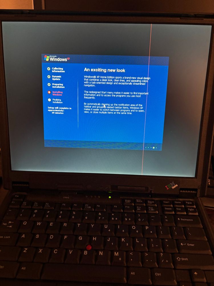 photo of a ThinkPad 390E running the graphical portion of the Windows XP setup. it's running in 256-color mode or something because everything is dithered to hell and back and it looks weirdly flat