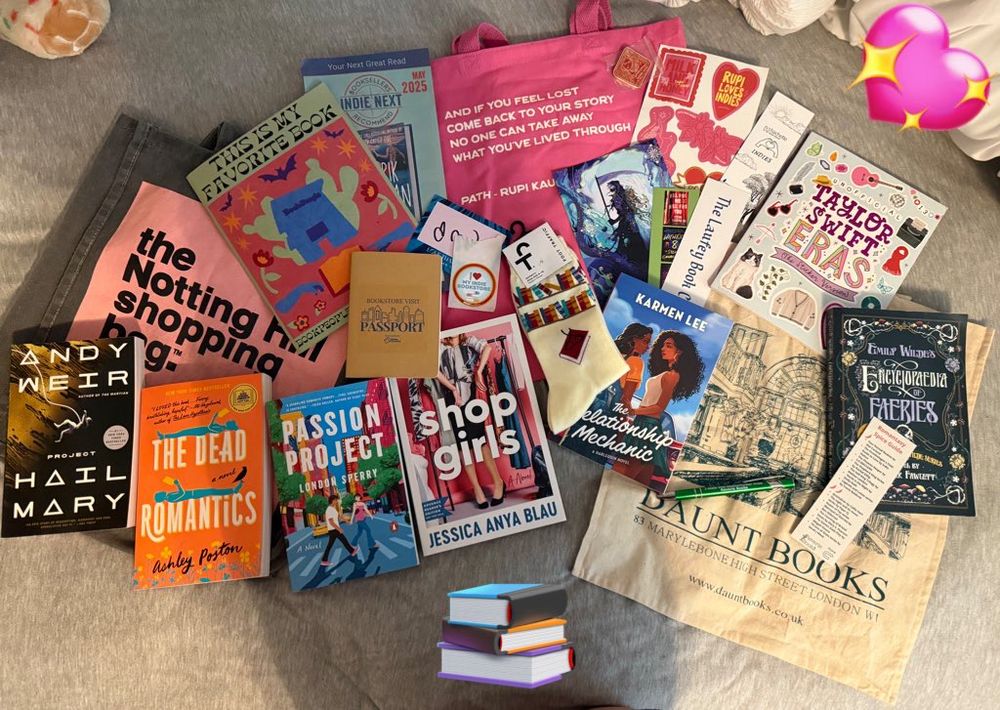 Books and tote bags and socks and stickers on a bed 