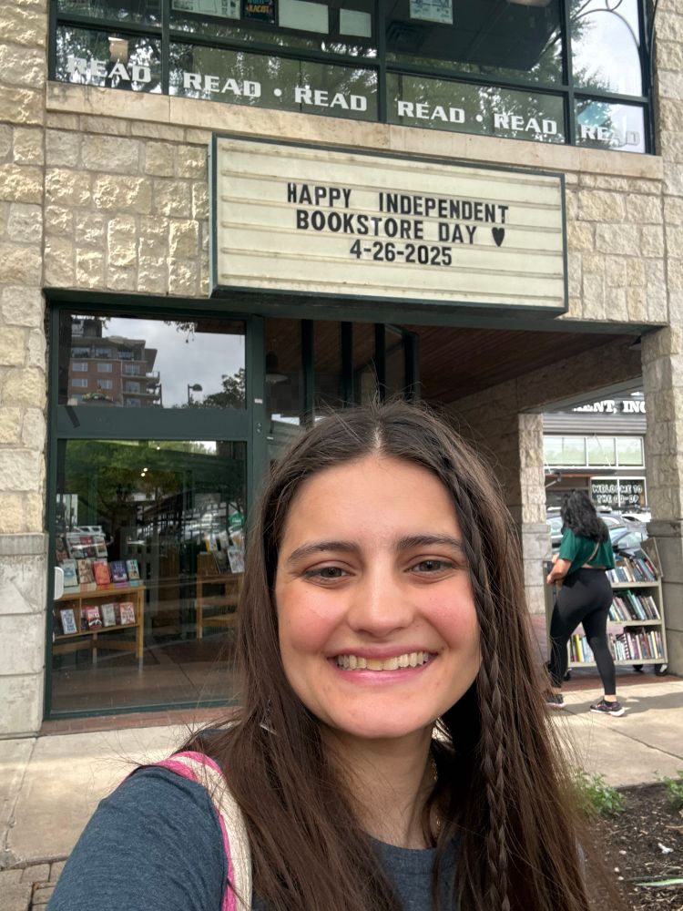 Girl in front of BookPeople bookstore that has a sign that reads “Happy Indie Bookstore Day”

