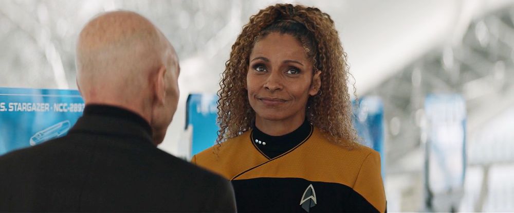 Four images of Picard season 2, episode 1. Raffi in her Starfleet uniform talking to Picard, grinning and winking at him. 