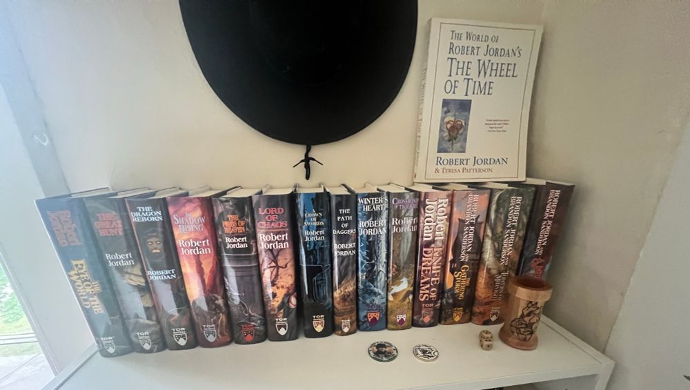 A white shelf holding all the wheel of time hardcovers with original cover artwork 
