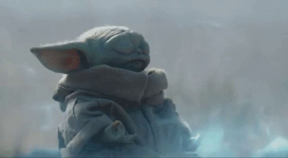 a baby yoda from star wars is sleeping in a blanket .