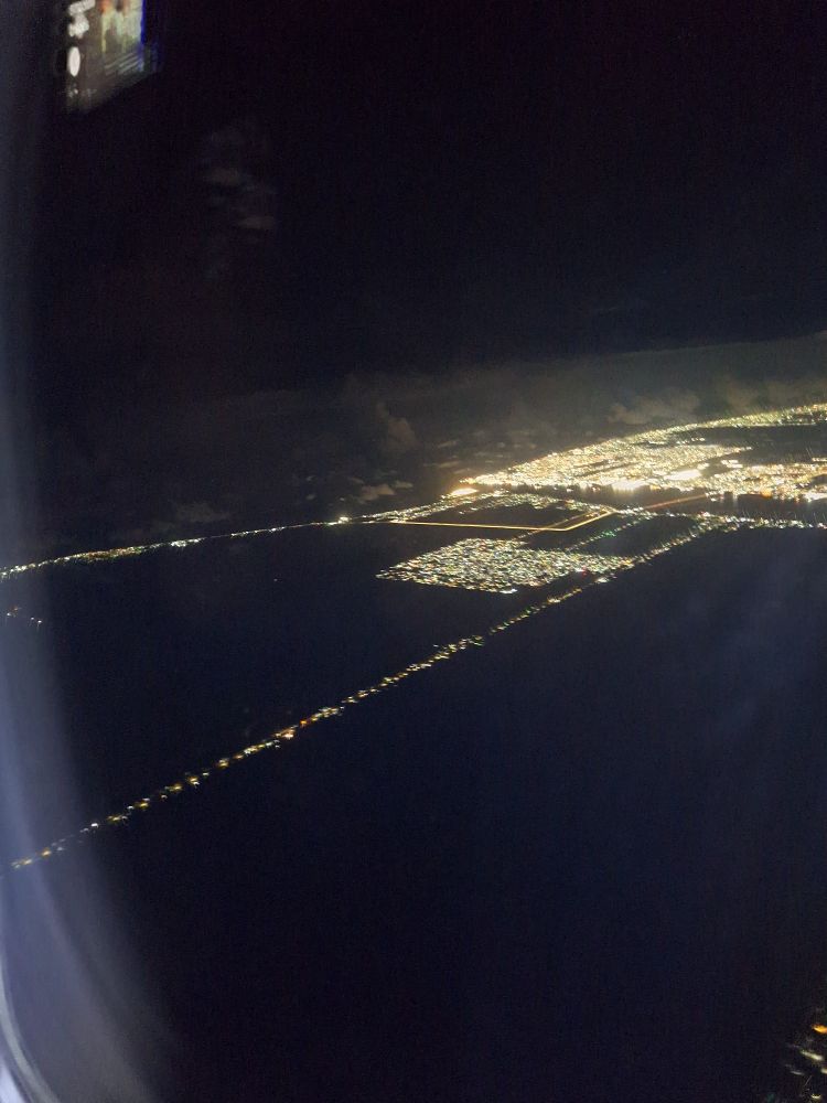 Georgetown Guyana through a plane windows at night. The ocean is the dark are at the top and the river is a narrow dark band with a lighted harbor bridge. As usual Pic from a plane windows do not give justice. 