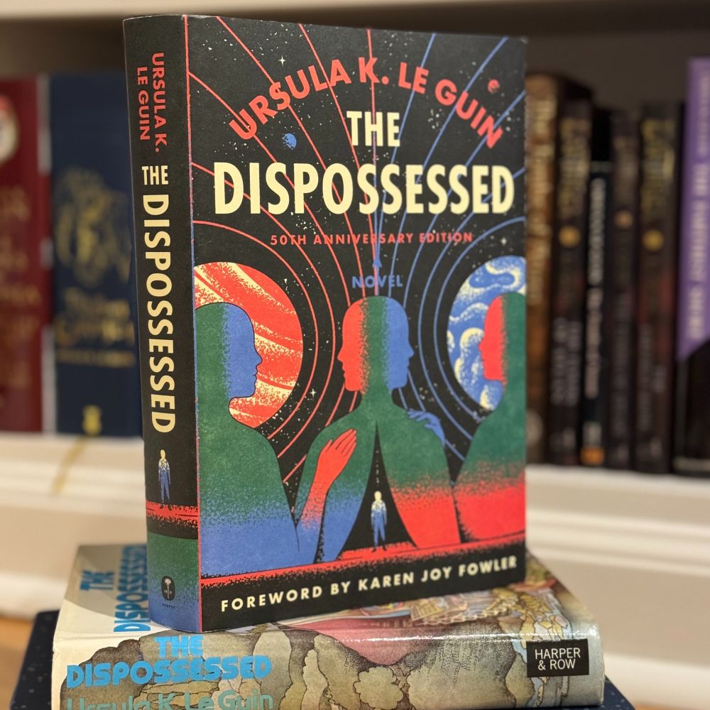 A copy of the 50th anniversary edition of The Dispossessed sits on top of the original edition of The Dispossessed.