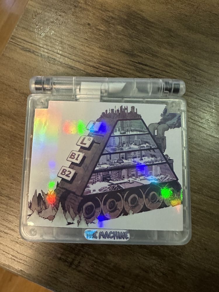 A transparent Gameboy SP with art inside of the shell depicting the main Machine from the game 'The Machine' It is a cutaway view map drawing from the collector's edition bonus materials. 