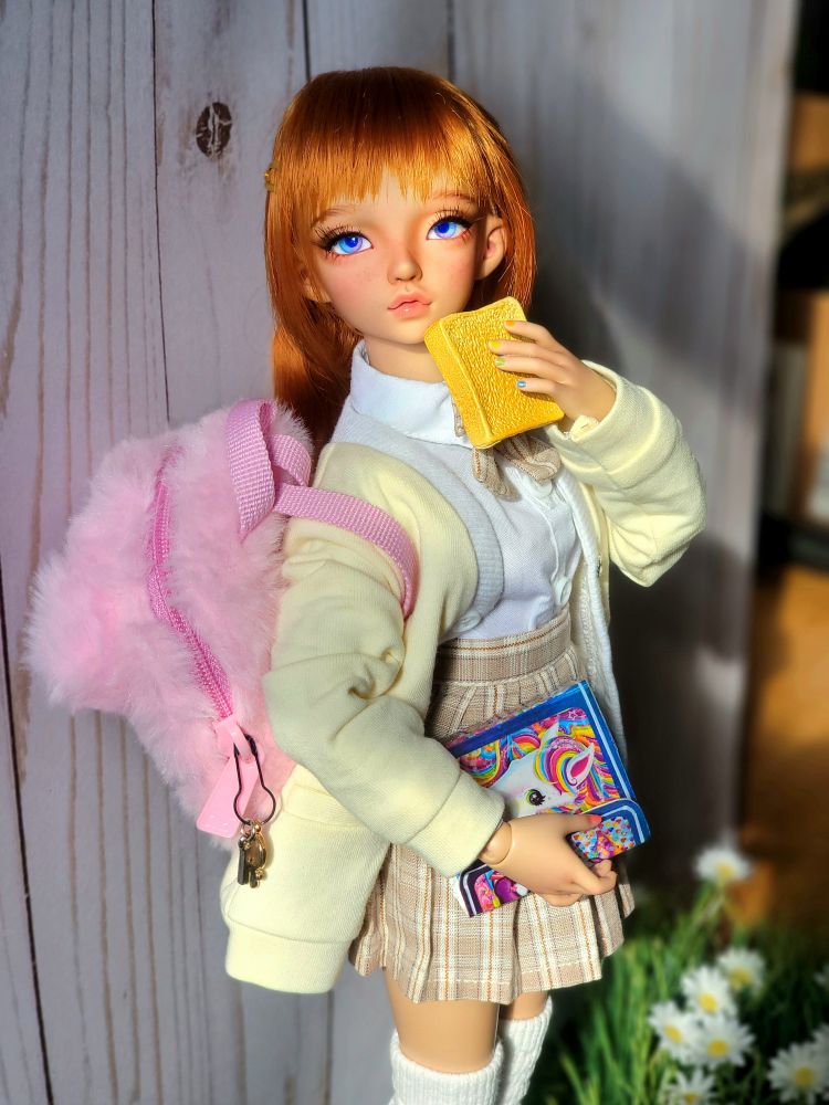 Minifee Phoeb with sweet expression and red hair wearing a school uniform of a white shirt and brown plaid skirt with a yellow sweater. She's carrying a pink fuzzy backpack and a Lisa Frank Trapper keeper. She holding a slice of toast. She's standing in front of a wooden fence and flowers.