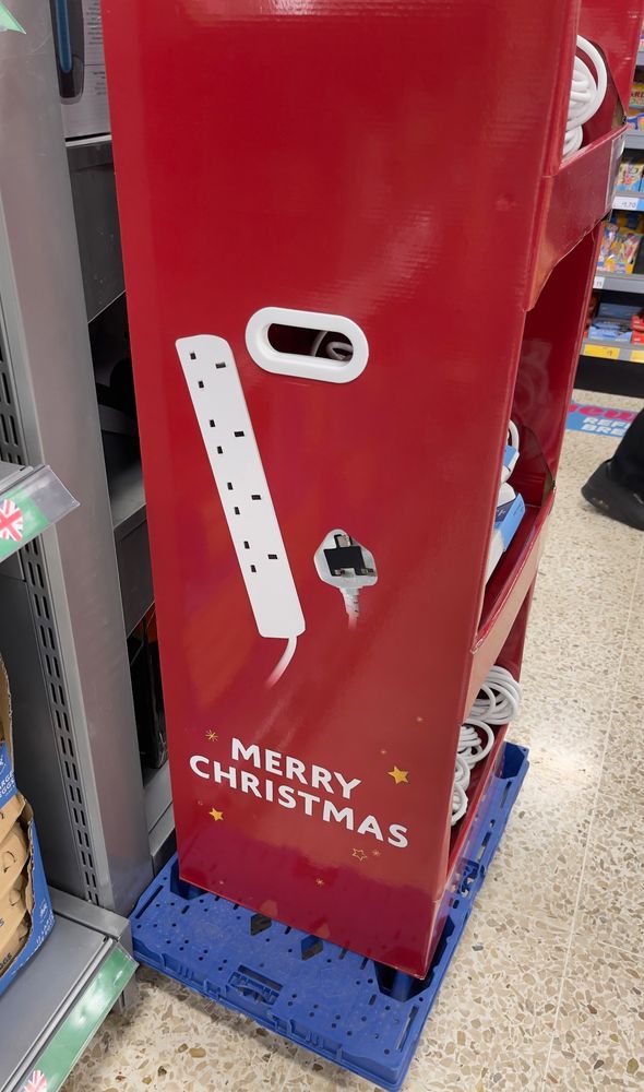 Supermarket display of mains extension leads emblazoned with the caption Merry Christmas 
