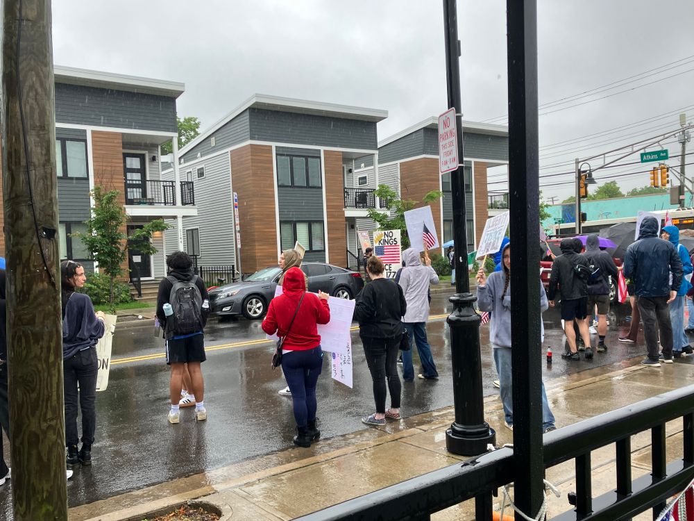 Rainy day people standing in street holding signs