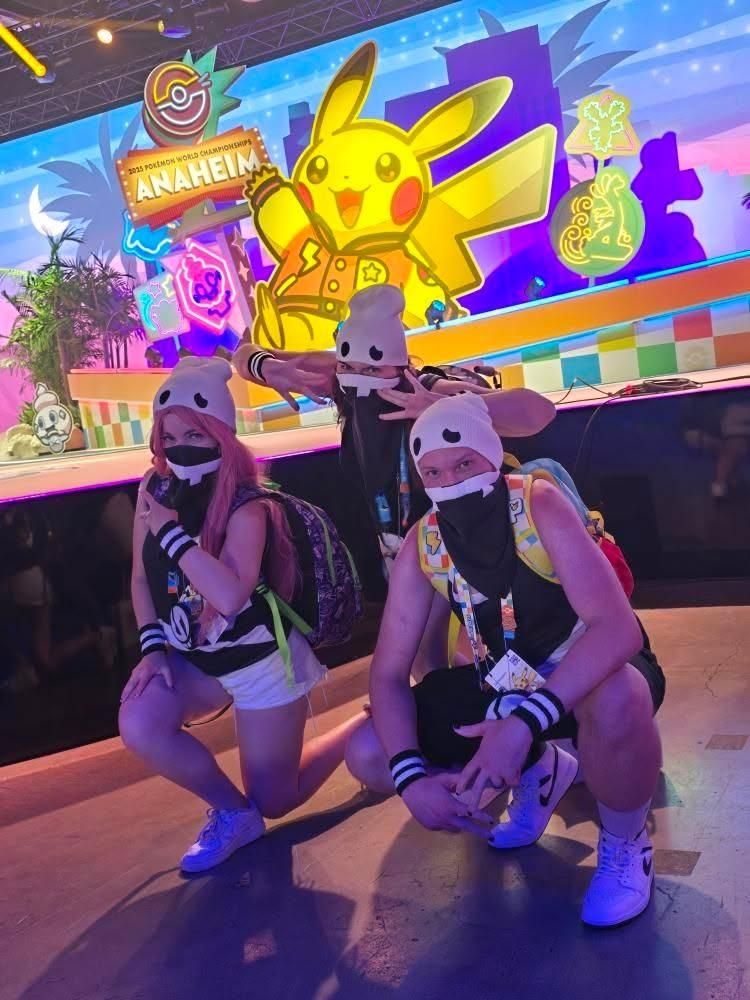 A picture of me, TJ, and Orrezon in our team skull grunt cosplays in front of the main stage at Pokémon Worlds 