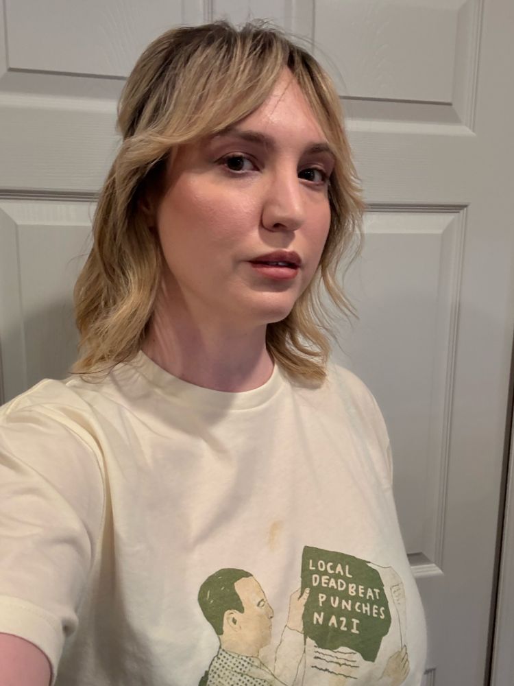 A woman with wavy shoulder length blonde hair looks at the camera. 