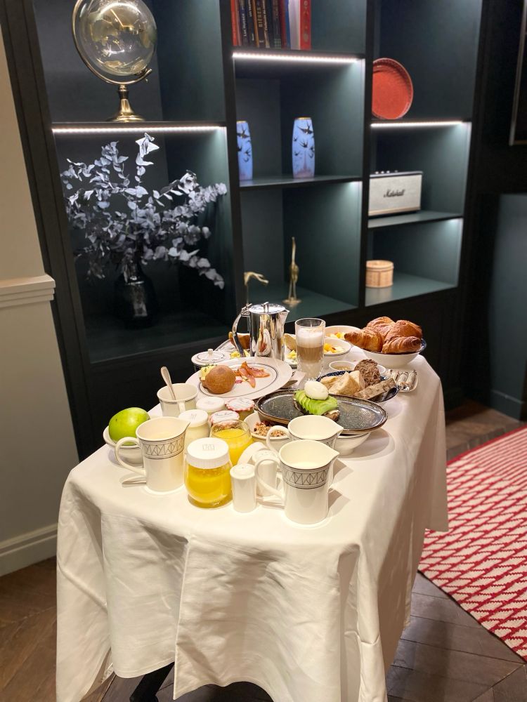 Room service breakfast in a little cart. The table has all sorts of desserts, dishes, and drinks