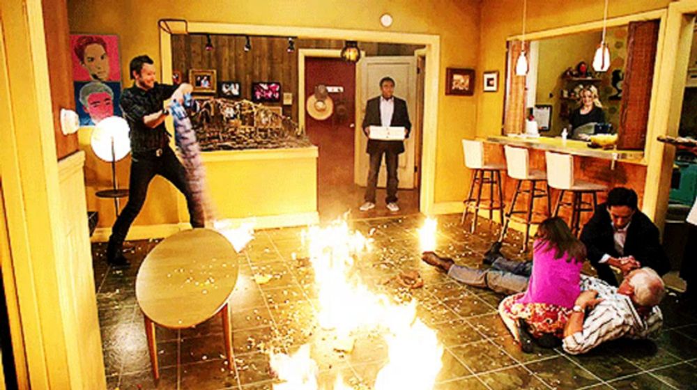 a group of people are gathered in a living room with a fire coming out of the floor