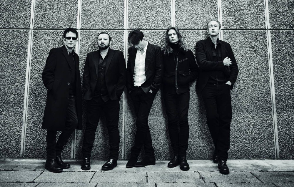 Suede also by Dean Chalkley in front of a pebbly wall (Southbank Centre?). A horizontal line has helpfully been carved into the wall to show us how tall Mat is. Brett has come over unaccountably camera-shy. Neil's cheekbones are exquisite.