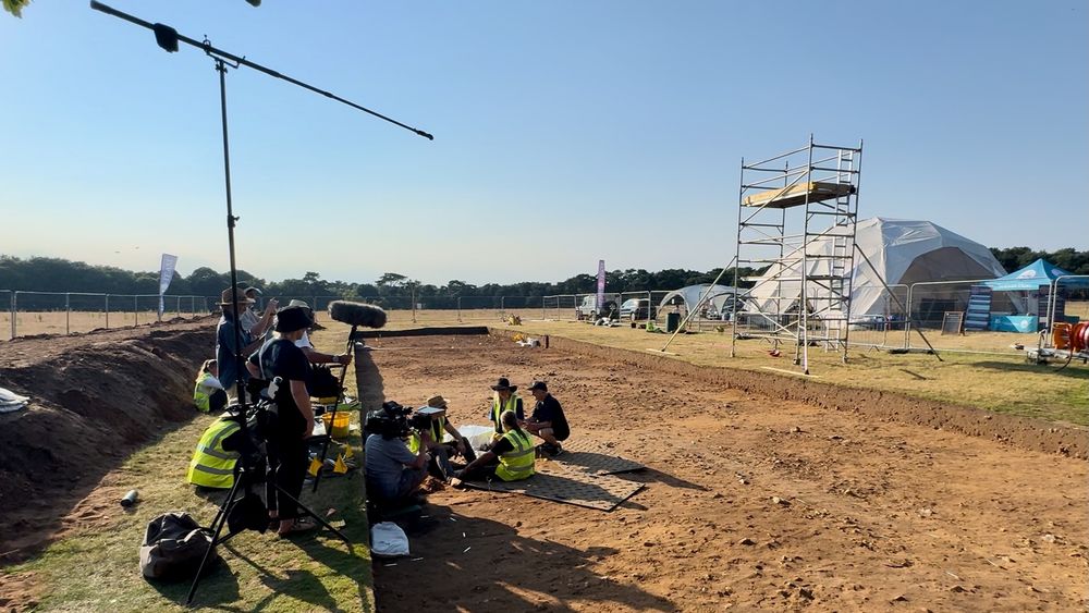 Photo of the remainder of the Bromeswell bucket being lifted at Sutton Hoo in 2024. In shot are those doing the lifting and the crew around them.