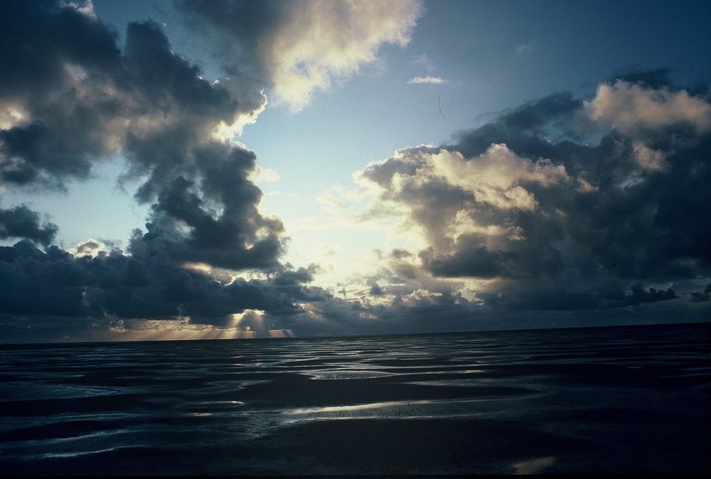 Wolkengebirge, durch das die Sonne scheint; über dem Watt