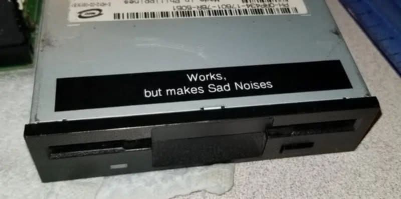 A machine with a sticker on it that says 'works, but makes sad noises'