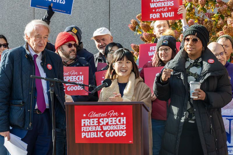 Ellen Mai, a federal worker unjustly fired by the USDA, stands behind a podium delivering remarks.

Photo courtesy of Tréa Lavery with MassLive